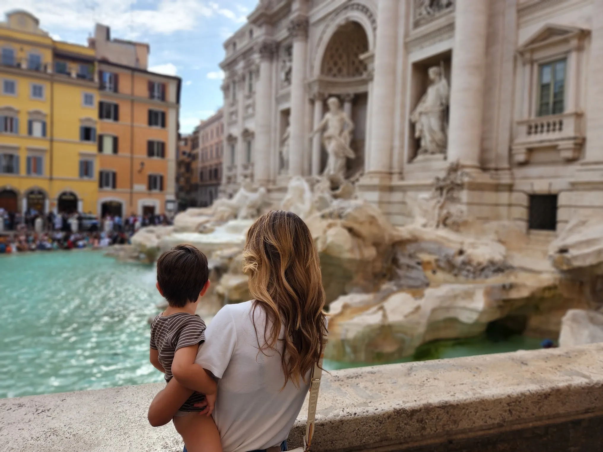 Mum holding her son as they look out over the Trevi Fountain in Rome.